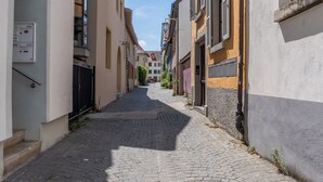 A cobblestone street between buildings with a mix of residential and commercial properties, including visible doors and windows. - Copper House - Old Town Constance (Konstanz)