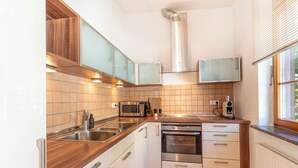 A modern kitchen with wooden cabinets, stainless steel appliances, and a window providing natural light. - Copper House - Old Town Constance (Konstanz)