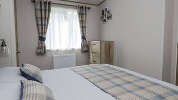 Un dormitorio con cama, radiador, armario de madera y ventana con cortinas.