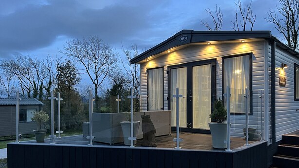 A modern, single-story cabin with a covered patio area, large windows, and a welcoming entrance. - Winscales Rest (Workington)