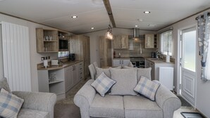 A compact living space with a kitchenette, a sofa, and a dining area. - Winscales Rest (Workington)