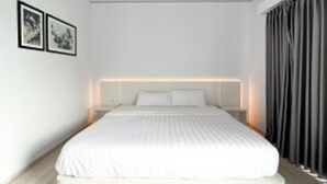 Une chambre moderne avec un grand lit, des murs blancs et un plancher en bois.