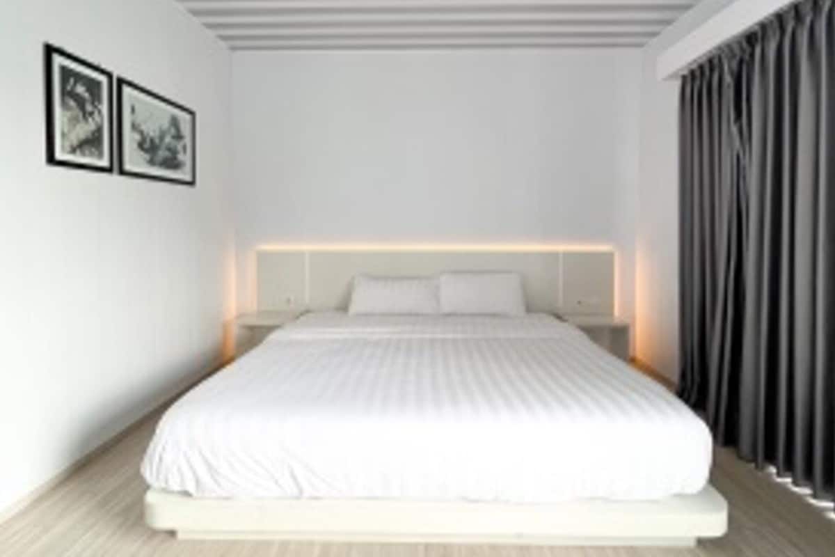 Ein modernes Schlafzimmer mit einem großen Bett, weißen Wänden und Holzboden.