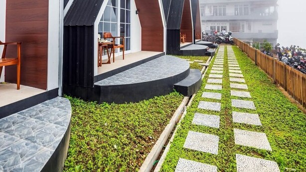 Une rangée de chalets modernes de style A, dotés d’espaces extérieurs aménagés pour s’asseoir et d’un chemin pavé.