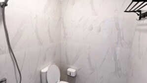 Une salle de bain avec des toilettes, une douche et un mur en marbre.