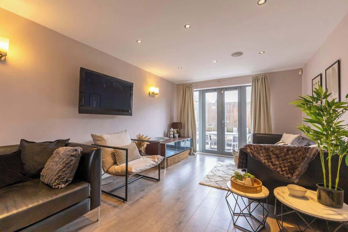 A modern living room with a sofa, armchair, and a dining area with a table and chairs.