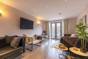 A modern living room with a sofa, armchair, and a dining area with a table and chairs.