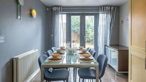 Comedor con una mesa dispuesta para seis, un radiador, un reloj y vistas al exterior.