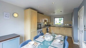 Una cocina moderna con armarios de madera, una mesa de comedor para cuatro personas y vistas al exterior.