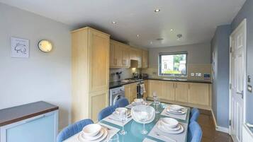 A modern kitchen with wooden cabinets, a dining table set for four, and a view of the outdoors.