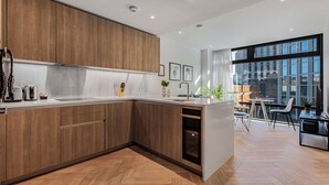 Une cuisine moderne avec des meubles en bois, un lave-vaisselle intégré et une grande fenêtre donnant sur la ville.