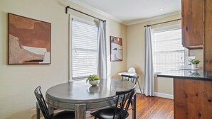 A dining area with a round table, black chairs, and a potted plant. - Midcentury Modern Home - Close to TCU/Dickies/Zoo! (Fort Worth)