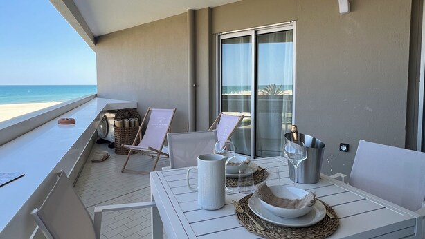 A balcony with a table set for two, overlooking a beach. - CANET SUD PANORAMIC SEA VIEW EXCEPTIONAL APARTMENT (Canet-en-Roussillon)