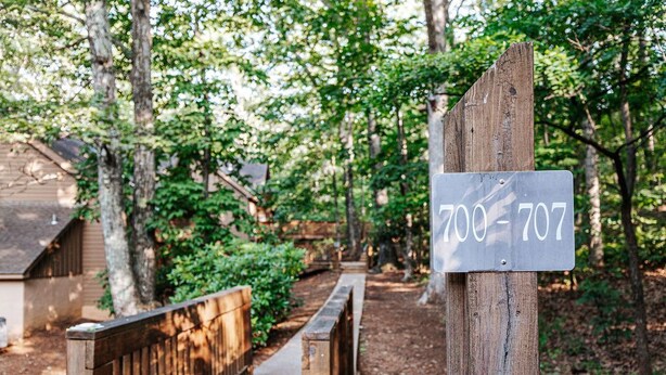 Ein hölzerner Weg führt zu einer rustikalen Holzhütte, deren Schild die Nummer 700-707 zeigt.