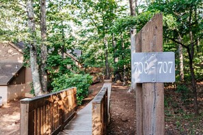 A wooden pathway leading to a rustic cabin with a sign displaying the number 700-707.