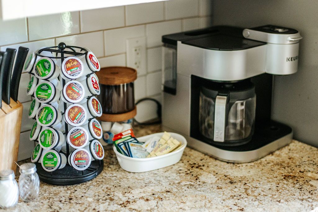 Een keuken met een koffiezetapparaat, een McCafé dispenser en een kruidenrek.