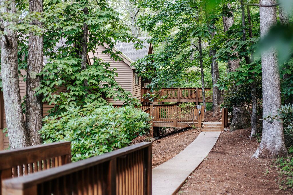 Une terrasse en bois menant à un chalet entouré d’arbres.