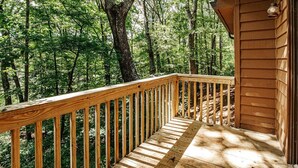 Eine Holzterrasse mit Geländer, mit Blick auf ein bewaldetes Gebiet.