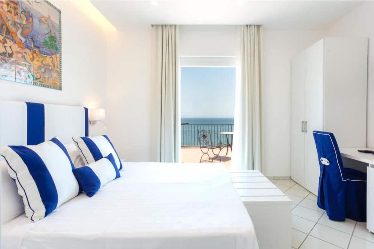Une chambre d’hôtel avec un lit, un bureau, une chaise et un balcon offrant une vue.
