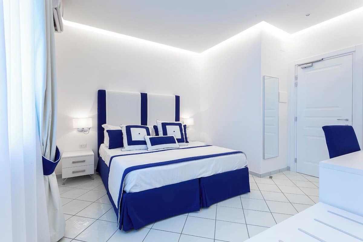 Une chambre d’hôtel moderne, dotée d’un grand lit, de tables de chevet, d’un bureau et d’une armoire.