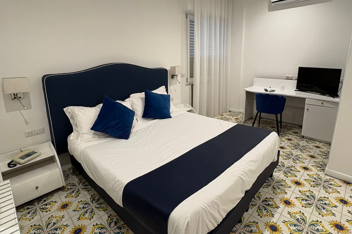 Une chambre d’hôtel équipée d’un lit, d’un bureau, d’une télévision et d’un appareil de climatisation.
