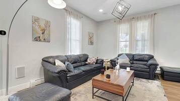 A modern living room with two black leather sofas, a wooden coffee table, and a large floor lamp.