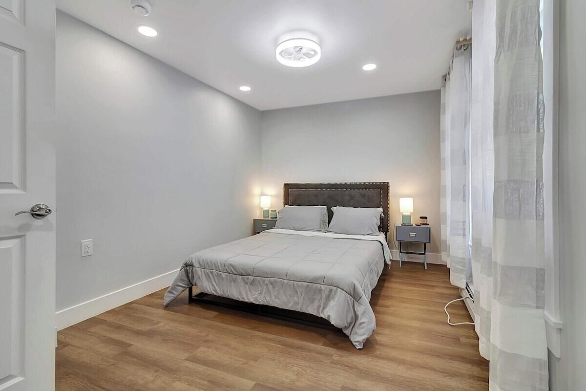 Un dormitorio con cama, mesitas de noche y lámpara de techo.