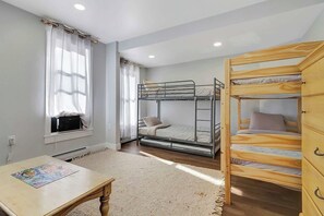 A room with bunk beds, a table with a puzzle, and a window with curtains.