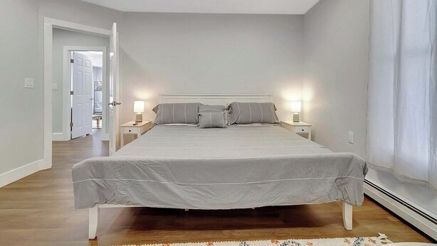 A bedroom with a bed, two bedside tables, and a nightstand. - 4BR Home | Walk Downtown Rutland + Trails (Rutland)