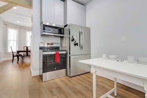 Una cocina moderna con electrodomésticos de acero inoxidable, una mesa de comedor y piso de madera.