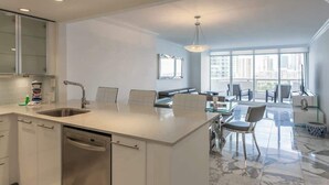 A modern kitchen with a central island, built-in appliances, and a dining area with a view of the city.