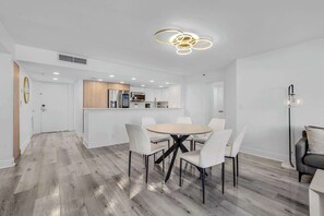 Une cuisine moderne avec des meubles blancs, un îlot central et un coin repas comprenant une table ronde et des chaises.
