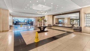 A spacious lobby with a reception desk, a chandelier, and a seating area.