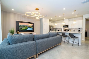 A modern kitchen with white cabinets, a central island, and pendant lighting.
