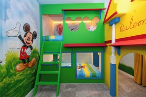 A children's room with a Mickey Mouse mural, bunk beds, and a play area.