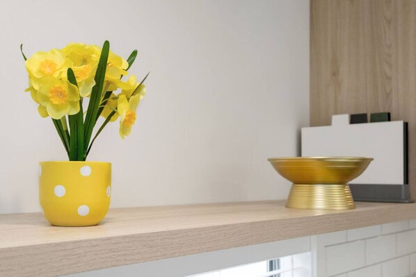 A yellow polka-dotted pot with flowers on a kitchen counter.