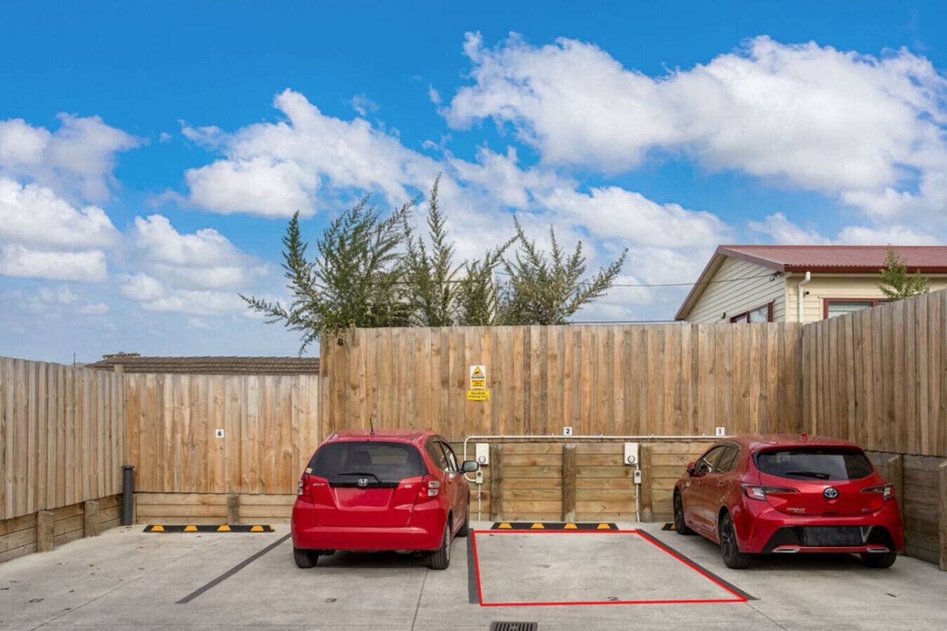 A gated parking area with two red cars parked.