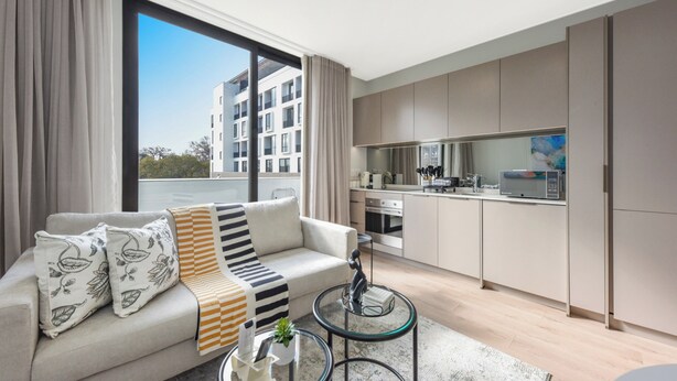 Un appartement moderne comprenant un canapé, une table basse en verre et un coin cuisine.