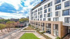 Un immeuble moderne à plusieurs étages, doté d’une cour intérieure, de balcons et offrant une vue sur le paysage environnant.