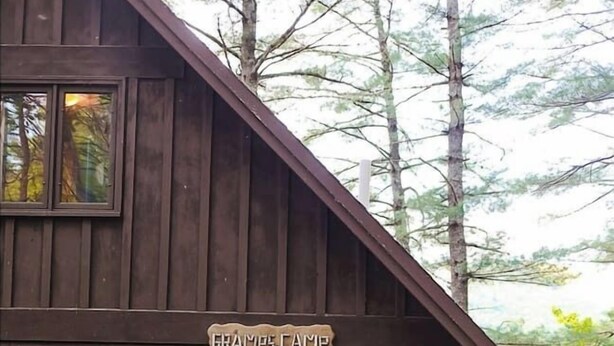 A rustic log cabin with a sign reading "GRAMP'S CAMP" and "EINA". - Gramps Camp • Moose Pond (Bridgton)