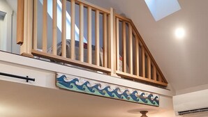 Une cuisine moderne avec un îlot central, un escalier en bois et une vue sur le ciel.