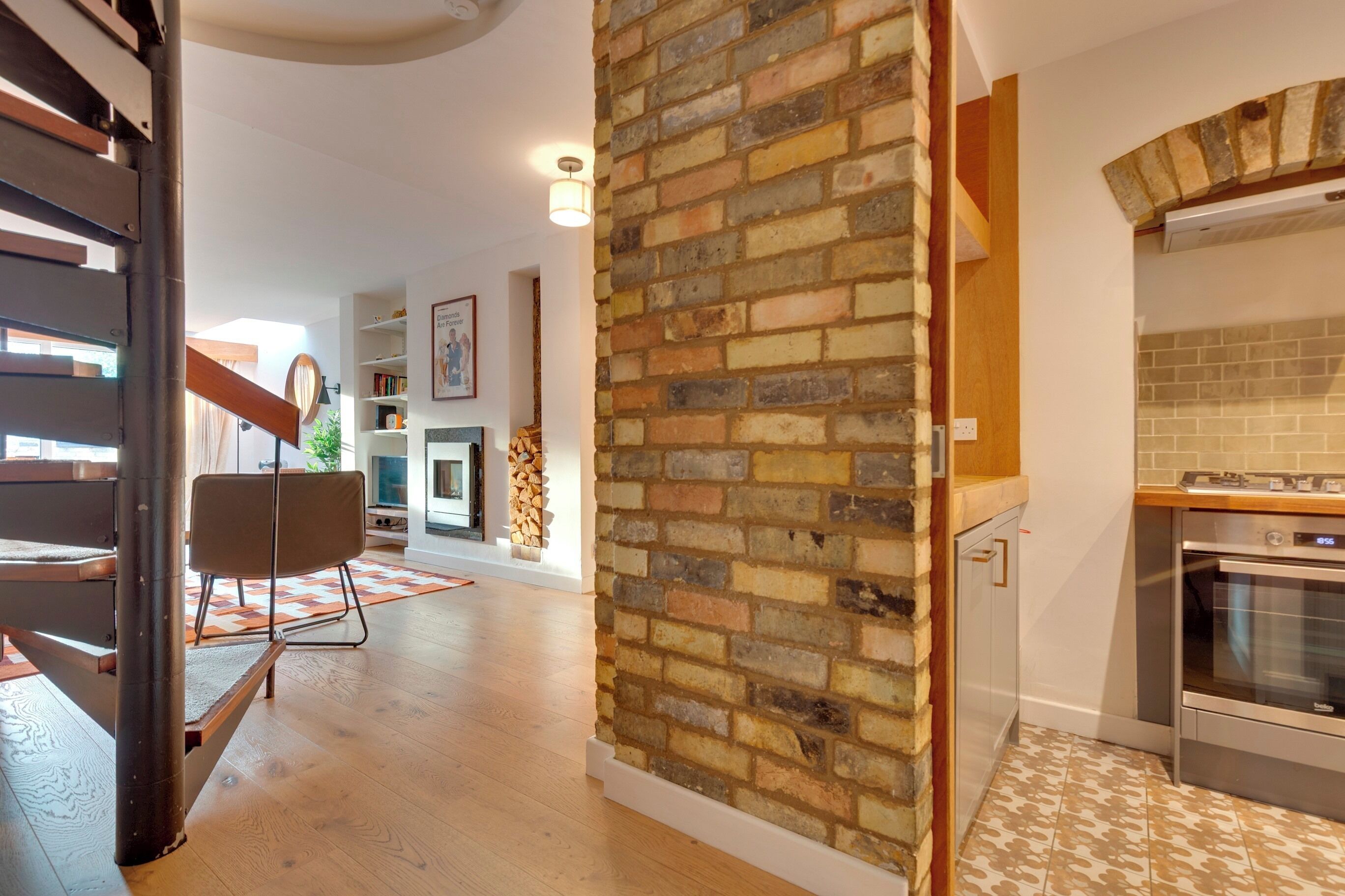 Une cuisine moderne avec un mur d’accent en briques, un plancher en bois et un four encastré.