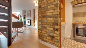 Une cuisine moderne avec un mur d’accent en briques, un plancher en bois et un four encastré.