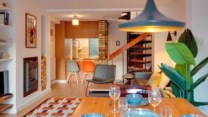 Un salon moderne comprenant un coin repas, une cheminée et un escalier menant à l’étage supérieur.