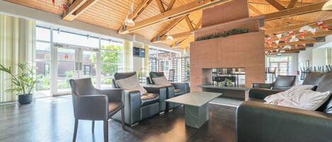 A spacious lobby with a high ceiling, leather seating, a fireplace, and large windows.