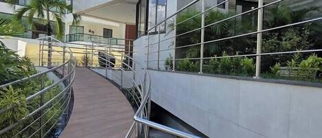 A modern building with a glass facade, outdoor stairs, and a wooden walkway.