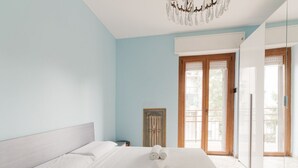 Une chambre à coucher avec un lit, un lustre, une porte à panneaux de verre et un tableau encadré au mur.