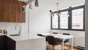 A modern kitchen with a white island, dark cabinets, and a large window with a view of buildings.