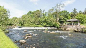 Un río con rocas, un pabellón y abundante vegetación.