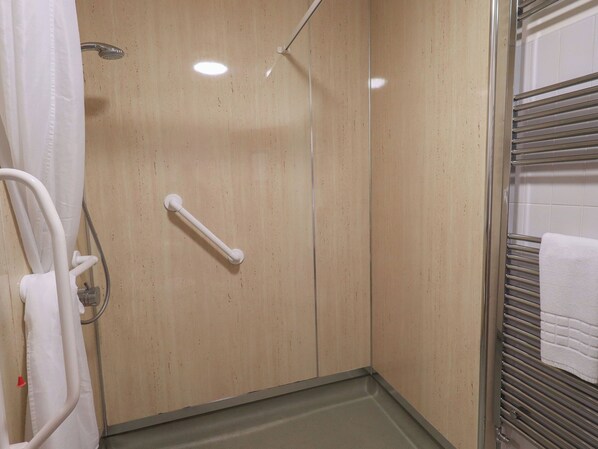 Une douche équipée d’une barre d’appui, d’un porte-serviettes et d’un rideau de douche.